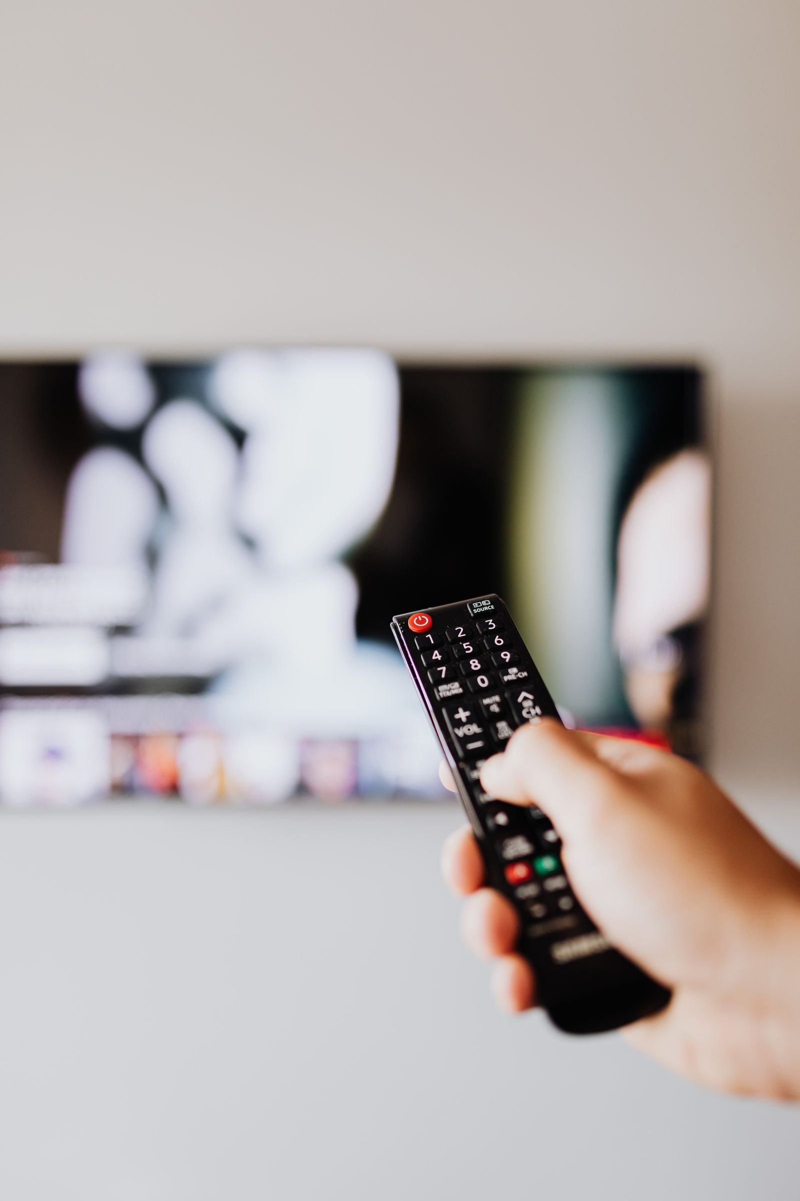 Hand bedient Fernbedienung vor TV Bildschirm